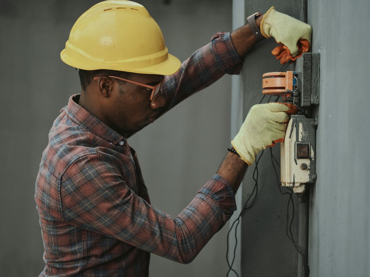 Technician in a hard hat installing equipment on site