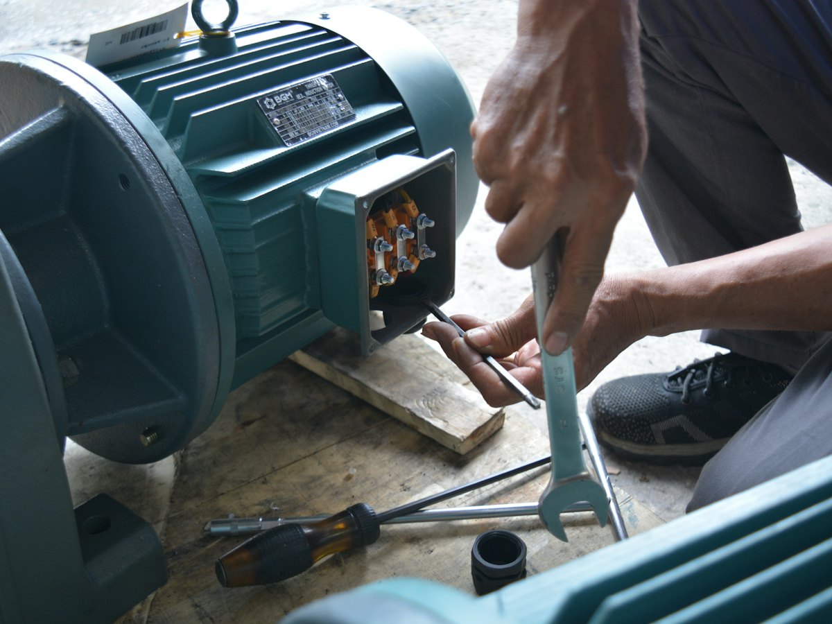 Technician servicing an electric motor with hand tools